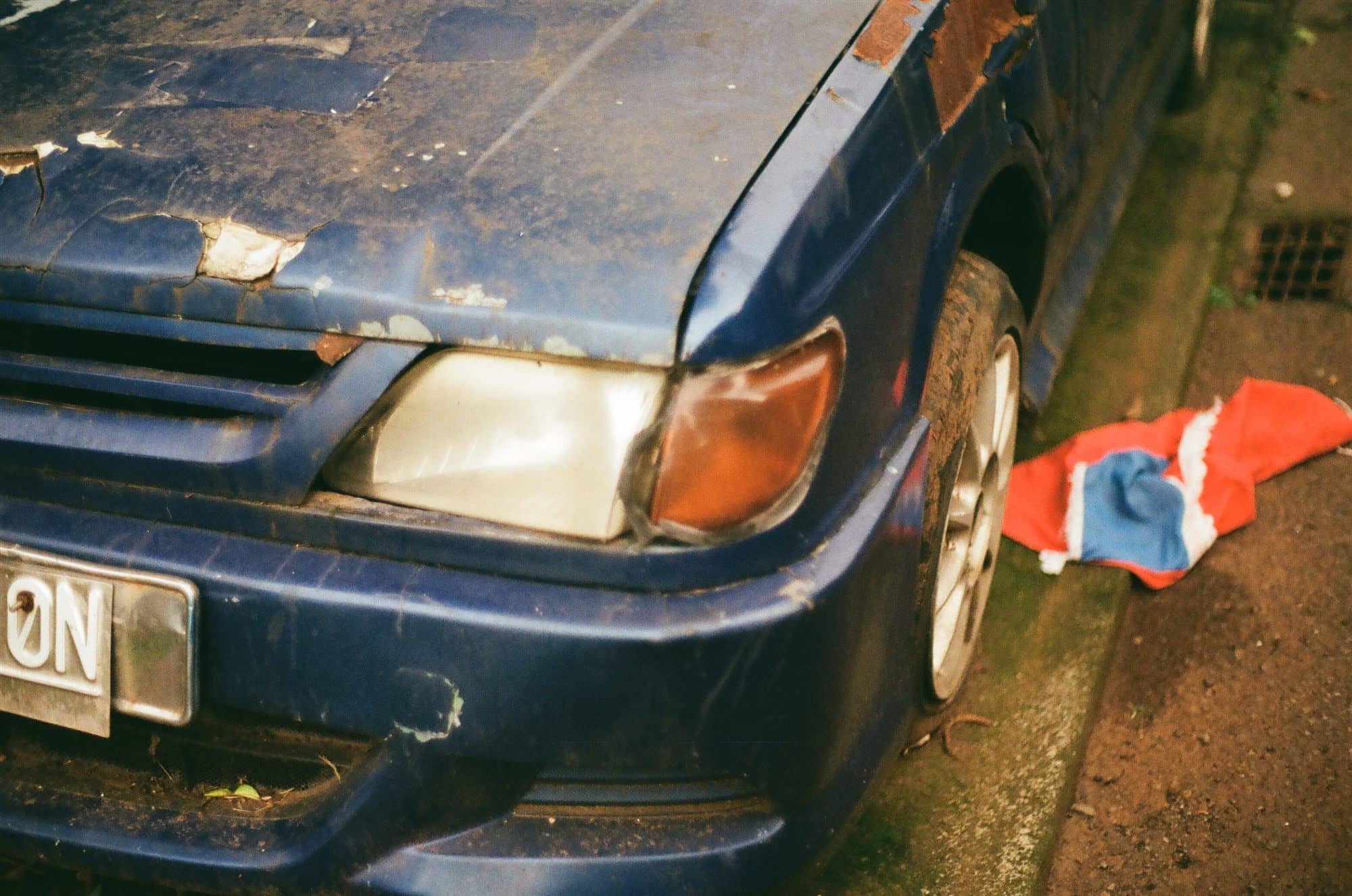 a weathered blue car and a fallen flag
