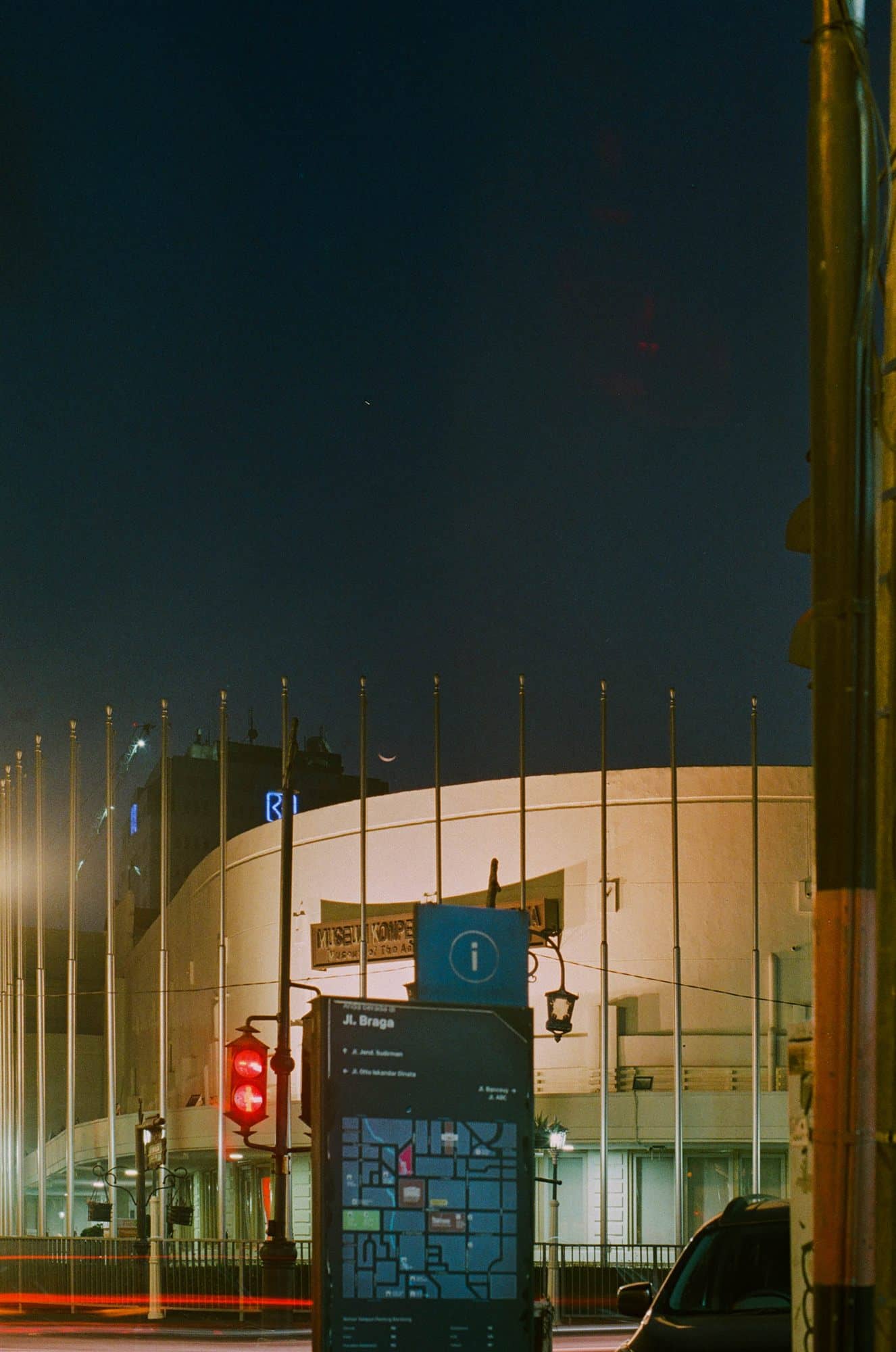 jl. braga at night: flagpoles and the curved face of a building
