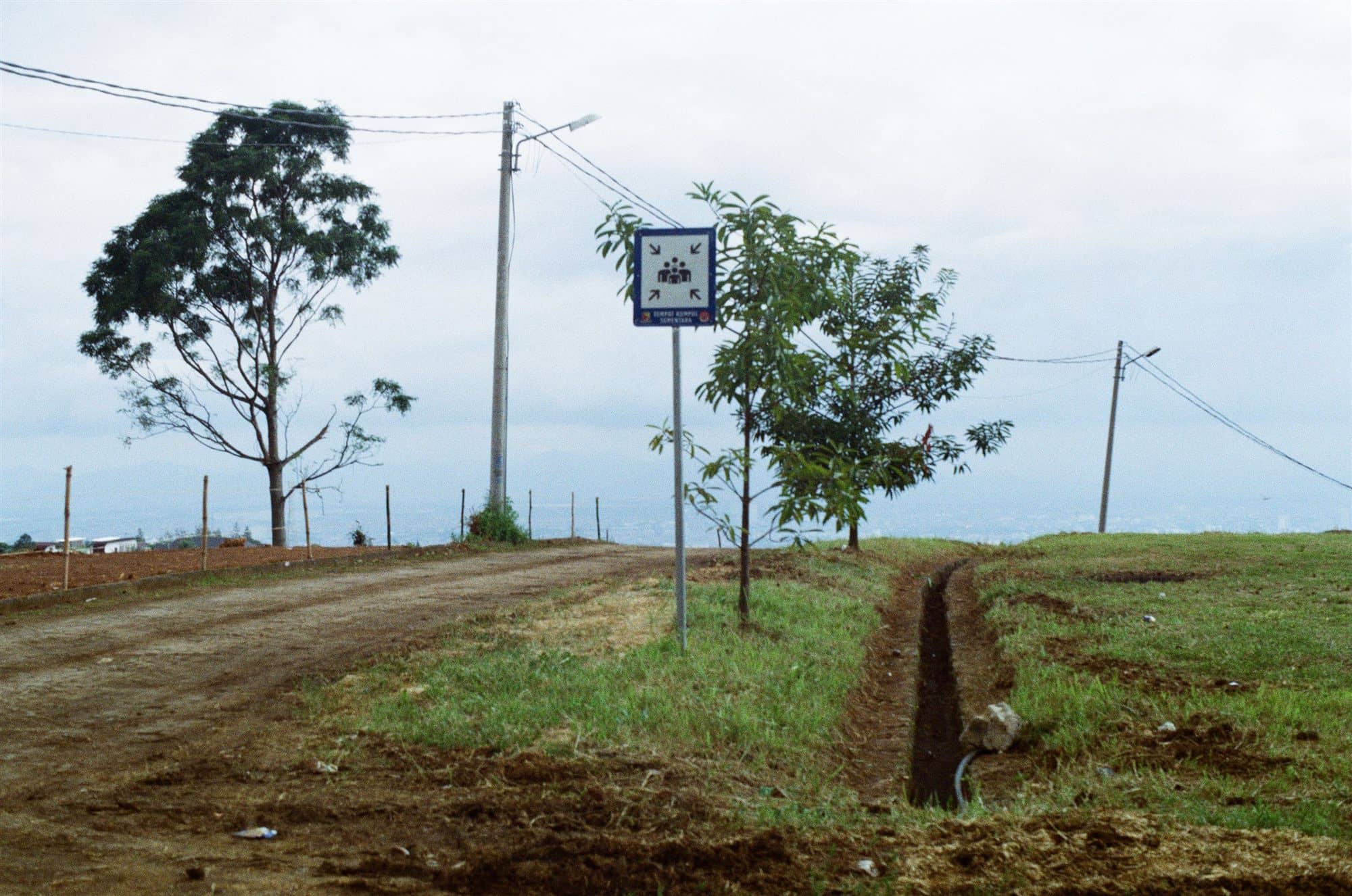 a dirt road, a crossing sign, the city far below
