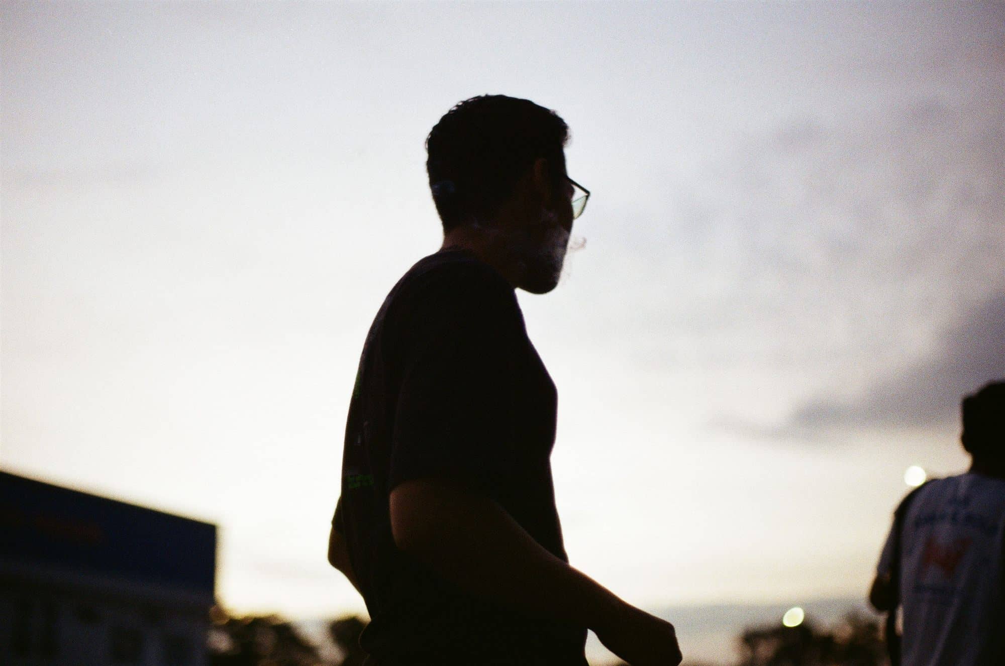 a silhouette exhaling smoke into the dusk