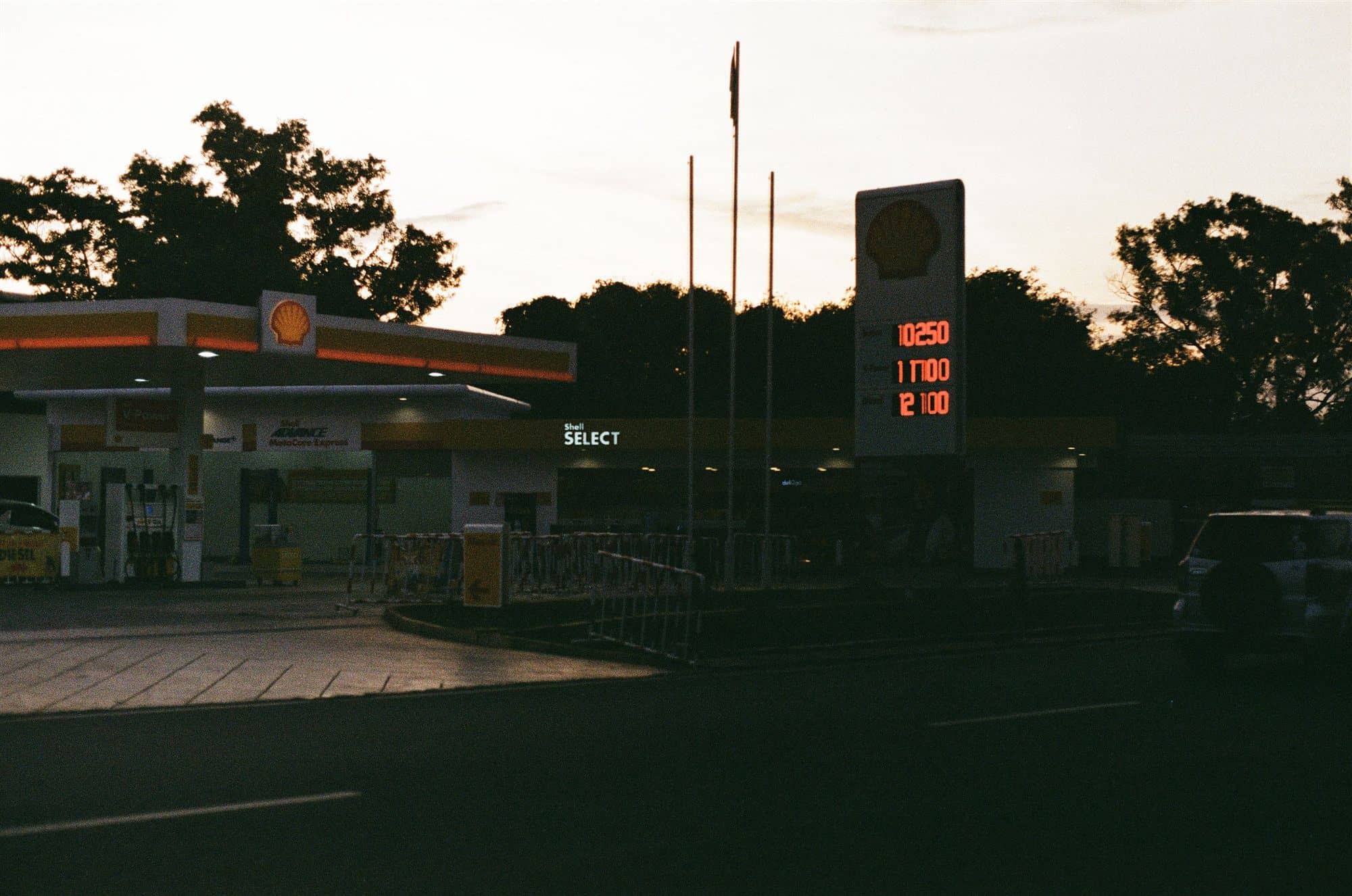 shell station at dusk, prices burning orange