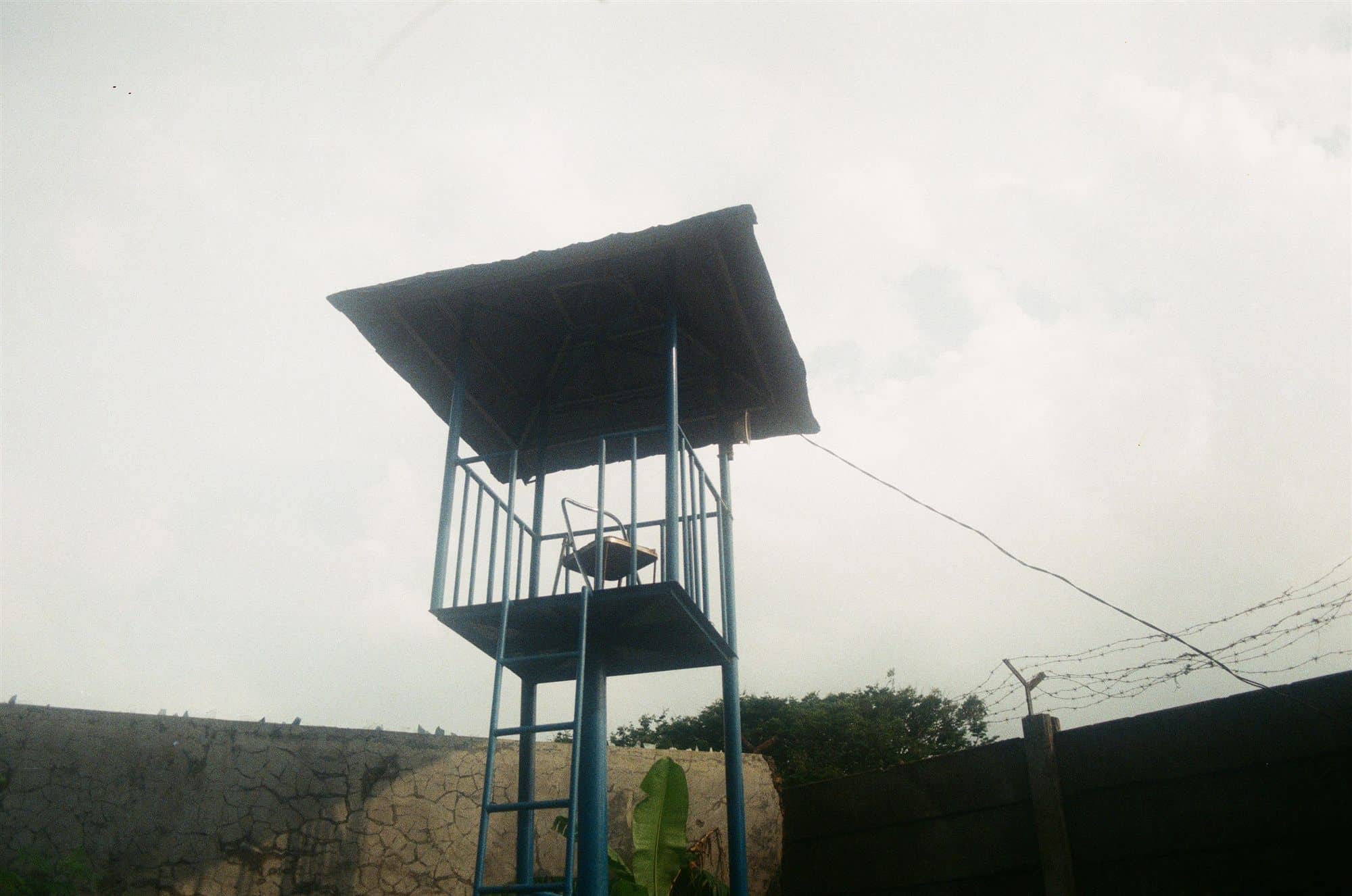 an empty watchtower with a plastic chair, barbed wire