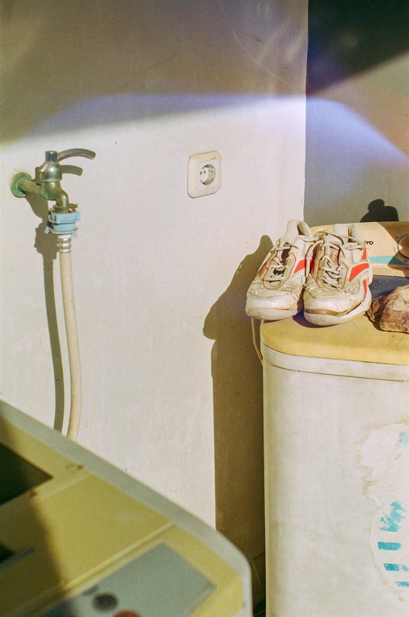 afternoon light on a tap, an old washing machine, a pair of worn sneakers